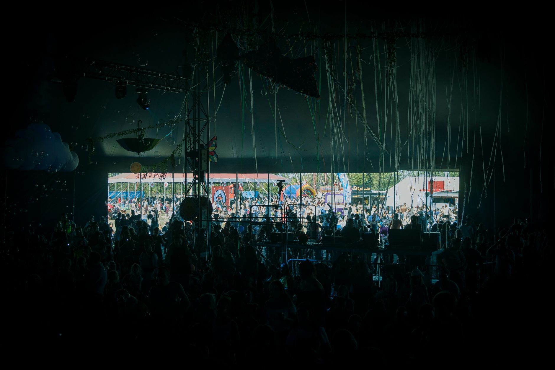 A crowd enjoying live music at a colorful outdoor festival stage.